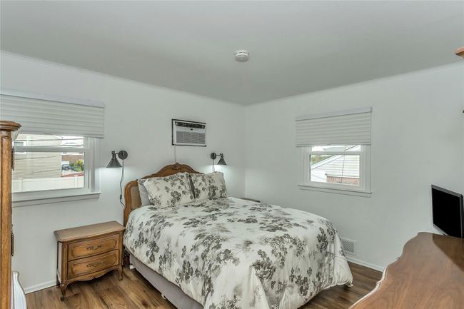 Bedroom with a wall mounted air conditioner, visible vents, and crown molding | Image 18