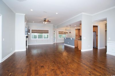 Unfurnished living room with crown molding, sink, dark wood-type flooring, and ceiling fan with notable chandelier | Image 3