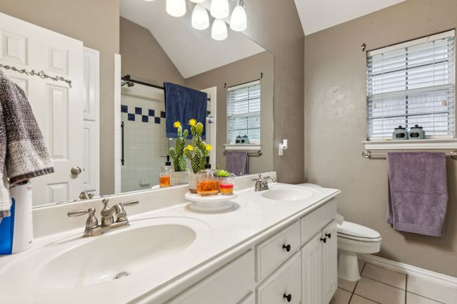 Bathroom featuring tile patterned flooring, a sink, lofted ceiling, and a tile shower | Image 19