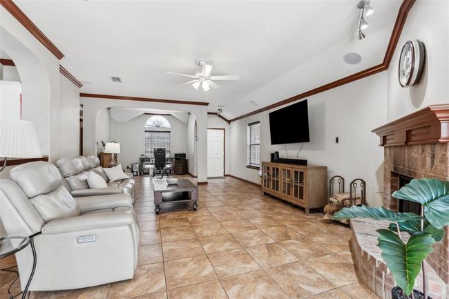 Living room featuring ornamental molding, arched walkways, a fireplace, light tile patterned floors, and ceiling fan | Image 18
