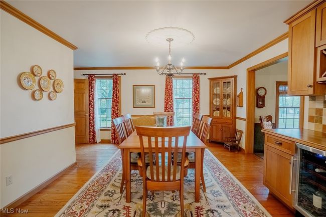 Dining room featuring wine cooler, crown molding, a chandelier, and light wood-style floors | Image 9