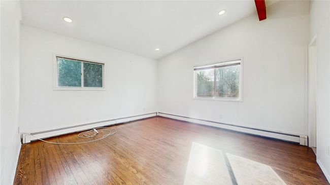 Spare room featuring recessed lighting, a baseboard heating unit, lofted ceiling with beams, and wood finished floors | Image 12