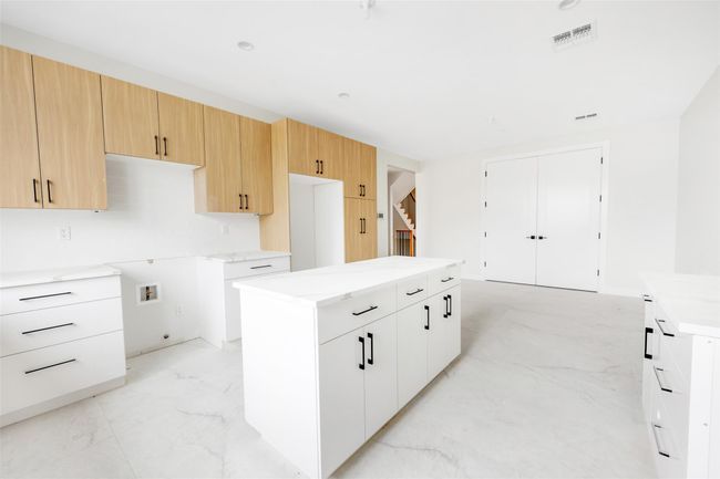 Kitchen featuring white cabinets, light brown cabinets, and a center island | Image 26
