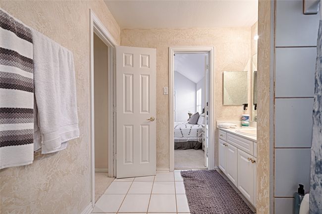 Bathroom with baseboards, a textured wall, ensuite bath, tile patterned flooring, and vanity | Image 17