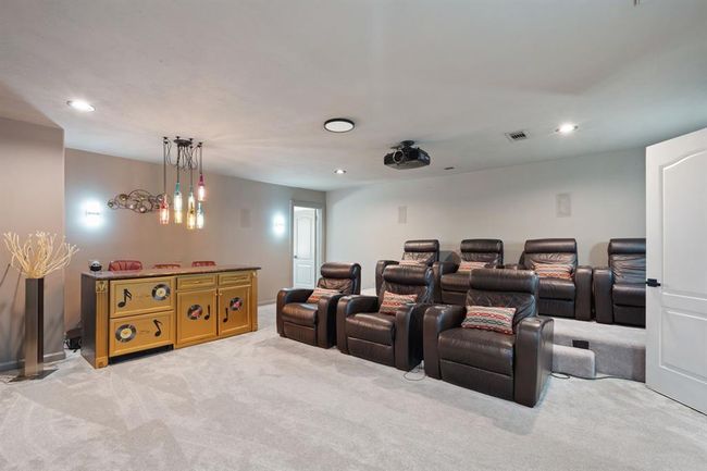 Another perspective of the media room, showcasing the eclectic light fixture and elevated seating. The projector and screen set the stage for an unforgettable movie experience. | Image 31