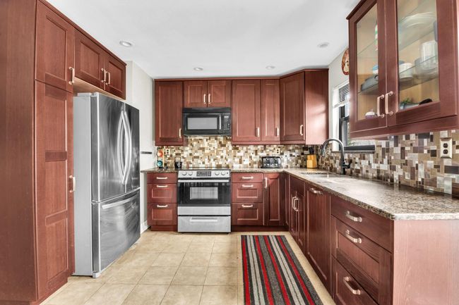 Kitchen featuring decorative backsplash, glass insert cabinets, stainless steel appliances, and a sink | Image 7