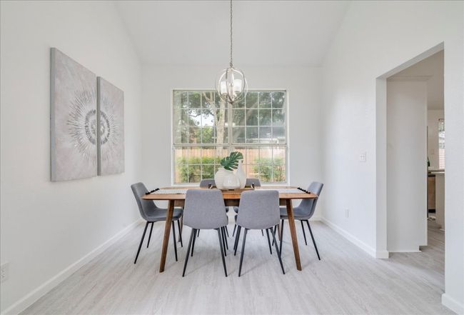 Dining area featuring a chandelier, vaulted ceiling, baseboards, and wood finished floors | Image 8