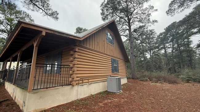 View of home's exterior featuring board and batten siding, cooling unit, and log siding | Image 6