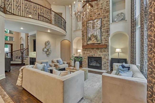 Two-story open family room with floor to ceiling stone fireplace and windows. | Image 4