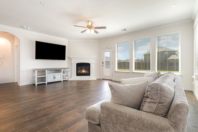 Living room with visible vents, ceiling fan, arched walkways, and wood finished floors | Image 4