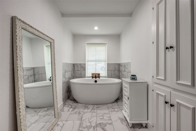 Full bathroom featuring marble look tile flooring, a soaking tub, wainscoting, tile walls, and recessed lighting | Image 12