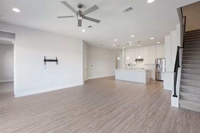 Unfurnished living room with stairs, a ceiling fan, recessed lighting, and light wood-style flooring | Image 5