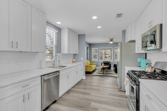 Kitchen with backsplash, a sink, stainless steel appliances, visible vents, and ceiling fan | Image 15