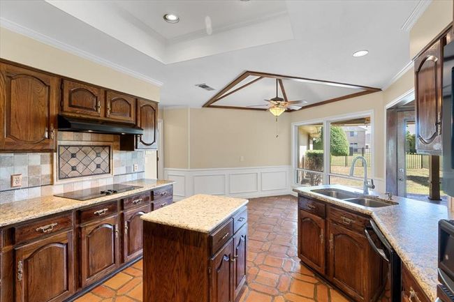 Kitchen featuring sink, light tile patterned flooring, a center island, and ceiling fan | Image 8