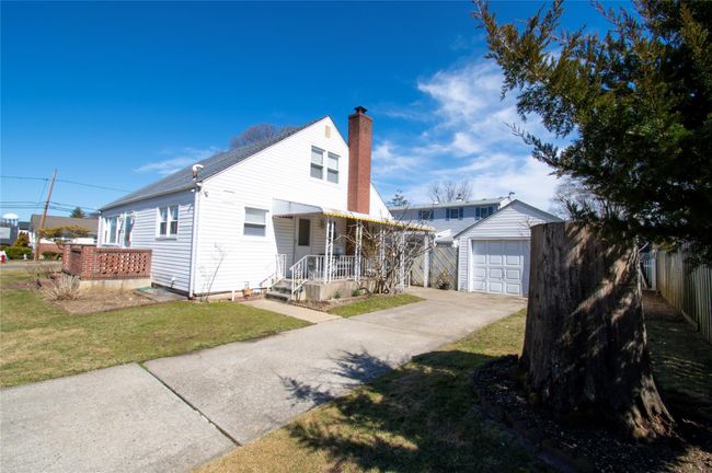 View of front facade featuring concrete driveway, a front yard, a chimney, a garage, and an outdoor structure | Image 6