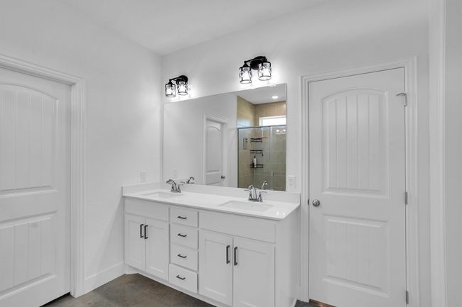 Bathroom featuring a shower stall, double vanity, and baseboards | Image 30
