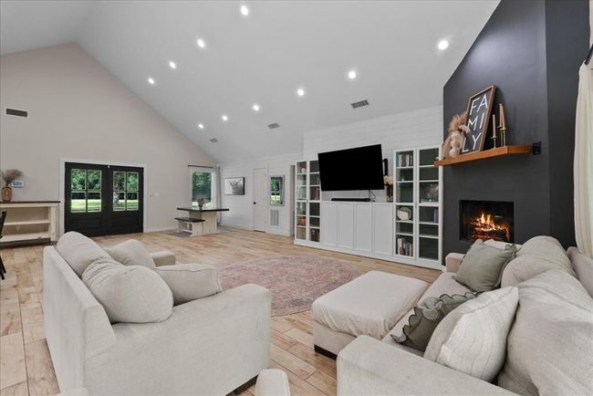 Spacious living room with vaulted ceilings, fireplace accent wall, and custom built-ins for a warm, inviting space. | Image 17