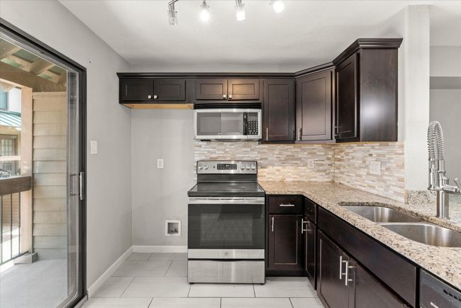 Kitchen with appliances with stainless steel finishes, light stone countertops, tasteful backsplash, dark brown cabinetry, and light tile patterned floors | Image 15