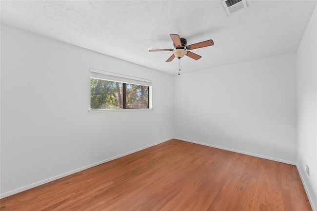 Bright and airy second bedroom with hardwood floors and a stylish ceiling fan, perfect for relaxation. | Image 17