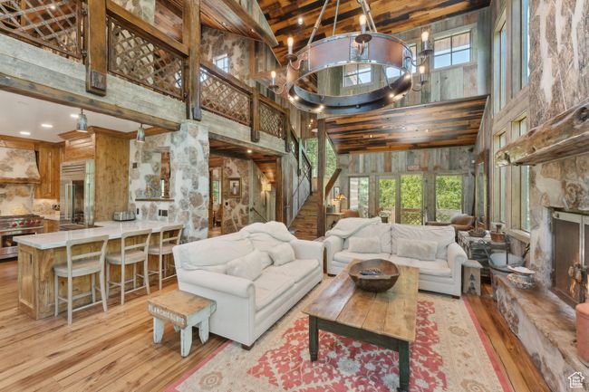 Living area with a towering ceiling, hardwood / wood-style floors, stairway, a chandelier, and wood walls | Image 5
