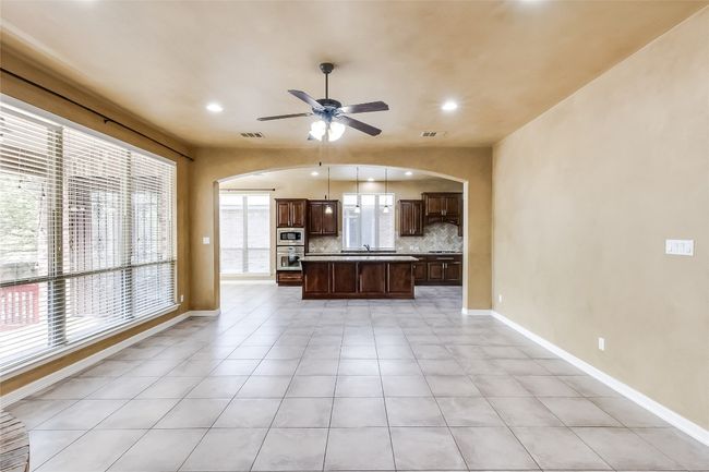 Kitchen with a center island, arched walkways, tasteful backsplash, and a ceiling fan in living area | Image 10