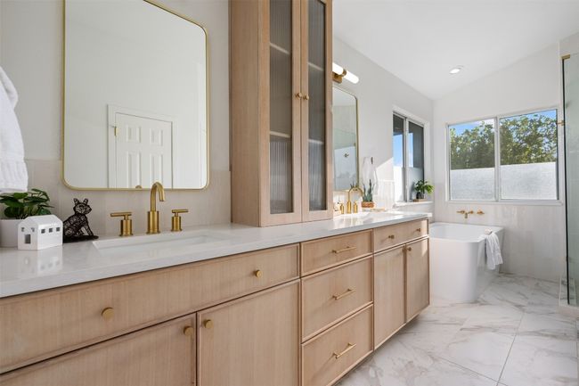 Bathroom with double vanity, a soaking tub, lofted ceiling, marble finish floor, and a sink | Image 26