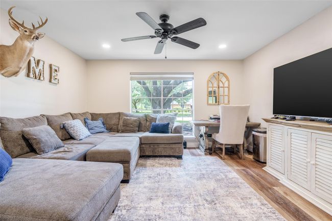 The home office or extra living room, is a perfect blend of functionality and comfort, featuring a window with privacy blinds, a ceiling fan for added comfort, and stylish vinyl plank flooring. | Image 6