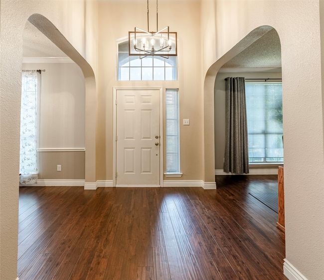Foyer entrance with arched walkways, crown molding, wood-type flooring, plenty of natural light, and a chandelier | Image 5
