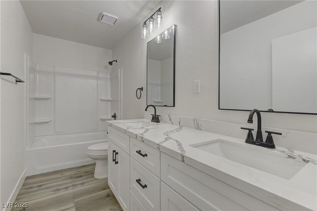 Full bathroom featuring toilet, wood finished floors, washtub / shower combination, and double vanity | Image 25