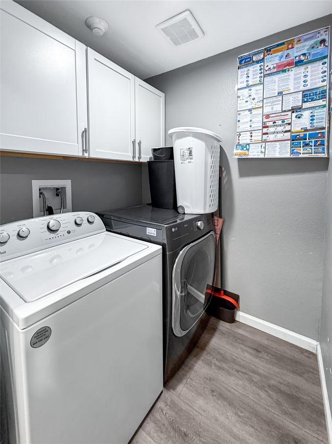 Laundry room with cabinet space, washer and dryer, and light wood finished floors | Image 21