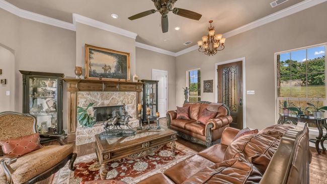 Living room with a ceiling fan, visible vents, a high end fireplace, wood finished floors, and recessed lighting | Image 10