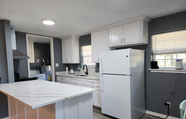 Kitchen with light granite countertops, white cabinetry, a sink, and freestanding refrigerator | Image 5
