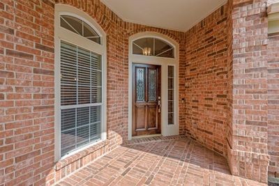 Covered front patio is all brick and provides shelter at the main entry. | Image 3