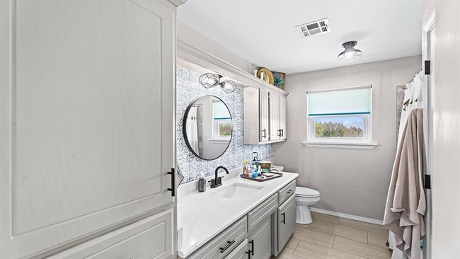 Bathroom with vanity, baseboards, toilet, visible vents, and decorative backsplash | Image 42