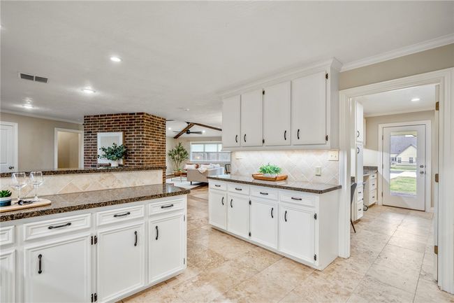 Kitchen featuring ornamental molding, dark stone countertops, visible vents, and white cabinets | Image 17
