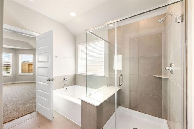 This additional view of the primary bath showcases a walk-in shower with tile surround and a separate garden tub perfect for soaking after a long day. | Image 11