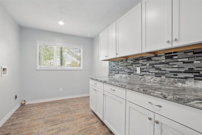 Thoughtfully designed for function and flow, the utility room features granite countertops and shaker-style upper and lower cabinets—offering ample storage and a convenient surface for folding, sorting, or organizing daily essentials. | Image 24