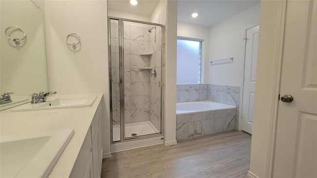 Full bathroom with a bath, a stall shower, wood finished floors, double vanity, and recessed lighting | Image 9