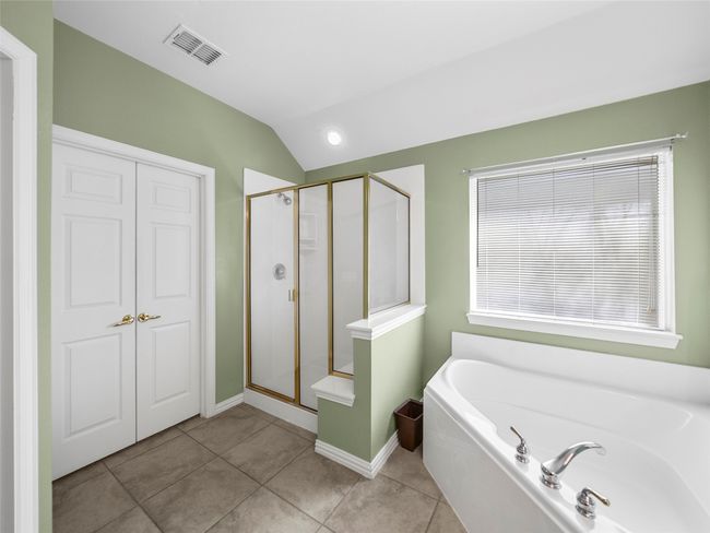 Bathroom with visible vents, tile patterned floors, vaulted ceiling, a shower stall, and a bath | Image 21