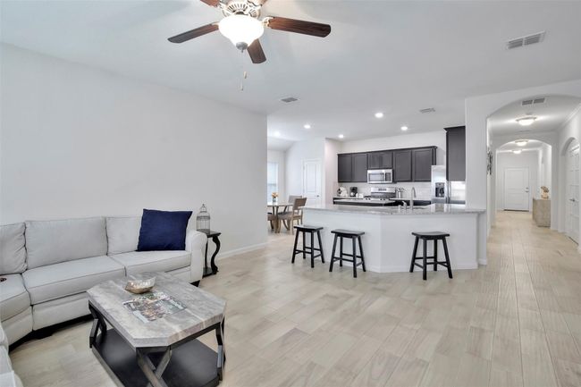 Living area with ceiling fan, arched walkways, recessed lighting, baseboards, and light wood finished floors | Image 12