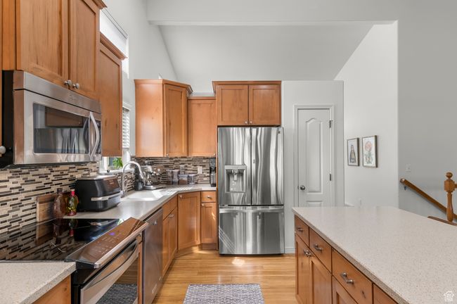 Kitchen featuring a sink, wood cabinetry, decorative backsplash, light wood-style floors, and stainless steel appliances | Image 6