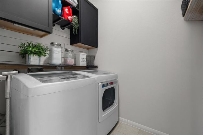 Laundry room featuring light tile patterned floors, cabinet space, independent washer and dryer, and baseboards | Image 32