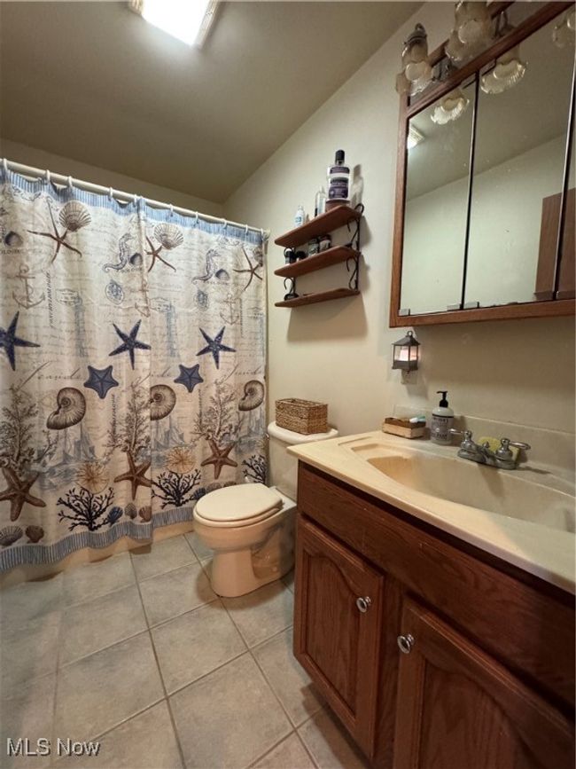 Full bathroom featuring toilet, vanity, tile patterned flooring, and curtained shower | Image 17