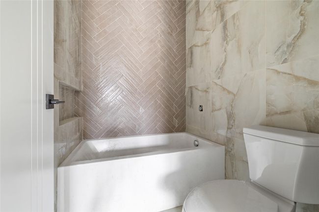 Full bath with tile walls, a tub, and toilet | Image 34