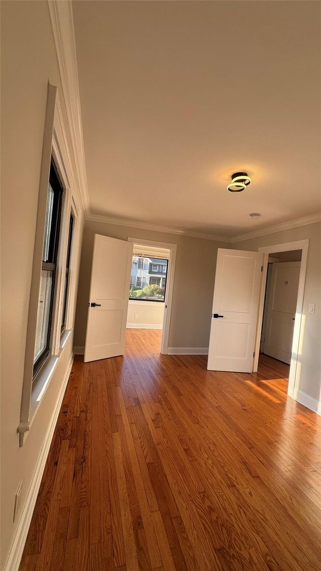 Spare room featuring crown molding and wood finished floors | Image 12
