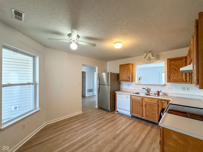 kitchen featuring freestanding refrigerator, visible vents, a sink, white dishwasher, and light wood finished floors | Image 7