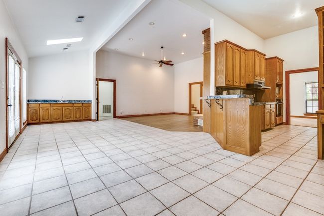 Kitchen with open floor plan, a peninsula, under cabinet range hood, a ceiling fan, and oven | Image 8