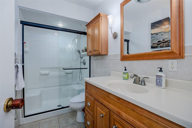 Full bath with vanity, a stall shower, tile patterned flooring, tile walls, and toilet | Image 25