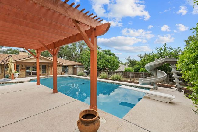 View of pool with a patio, a pergola, a fenced backyard, a water slide, and a diving board | Image 30