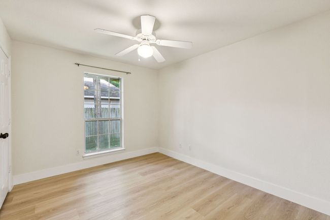 Empty room with light wood-style floors and ceiling fan | Image 16
